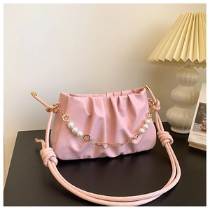 Detail of pink ruched cloud bag with golden flower accents and pearl chain strap