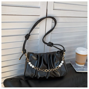 Detail of black pleated cloud bag with elegant pearl chain and adjustable knot strap
