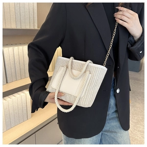 Detail einer beigen gewebten Mini-Eimertasche mit dicken Kordelgriffen und Goldkette