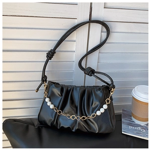 Detail of black pleated cloud bag featuring pearl chain and gold flower accents