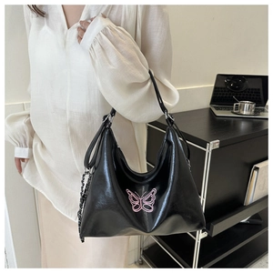 Detail of black glossy shoulder bag with pink butterfly embroidery and metal chain