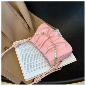 Close-up of pink ruched cloud bag with pearl chain and golden flower charms