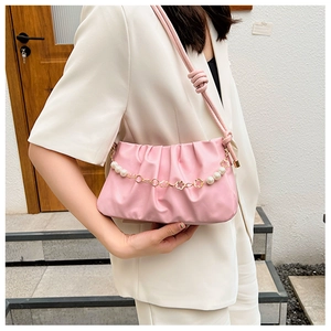 Detail of pink pleated cloud bag featuring pearl and golden flower decorative chains