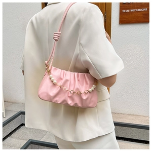Detail of pink ruched cloud bag featuring pearl and golden flower charm strap