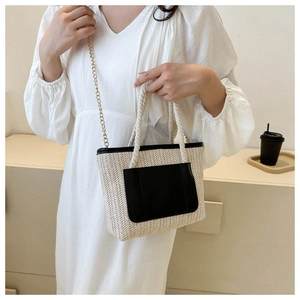 Detailansicht der gewebten Strohtasche mit schwarzer Ledertasche und Kettenriemen