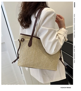 Détail d'un grand sac cabas en paille avec lanières en cuir brun et cordons latéraux