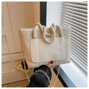 Detailaufnahme der weißen Stroh-Eimertasche mit Goldkette und geflochtenem Seilgriff