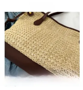 Détail du sac cabas en paille tressée avec poignées en cuir brun et base renforcée