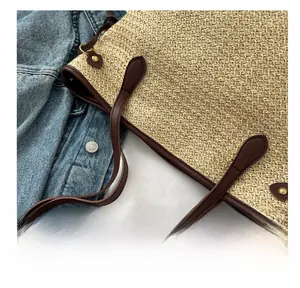 Détail du sac en paille tressée avec anses en cuir marron et rivets dorés