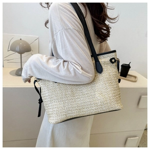Détail d'un grand sac fourre-tout en paille avec lanières en cuir noir et rivets dorés