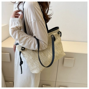Détail du sac cabas en paille d'été avec anses en cuir noir et texture tressée