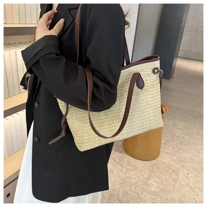 Détail d'un grand sac cabas en paille avec lanières en cuir marron et pompons décoratifs