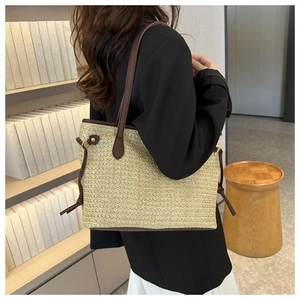 Vue détaillée d'un sac cabas en paille tressée avec lanières en cuir marron et texture