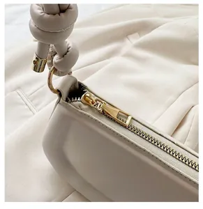 Détail de la fermeture éclair dorée et bandoulière nouée sur sac à main crème