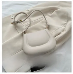 Comparaison de taille d'un sac demi-lune crème à côté d'un smartphone sur une veste