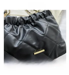 Close-up of black quilted leather bucket bag with gold chain strap and metal trim