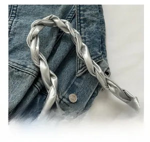 Close-up of silver woven knot handle with metallic texture on pleated tote bag