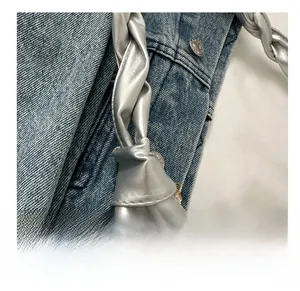 Detail of silver pleated handbag featuring a thick braided handle and metal zipper closure