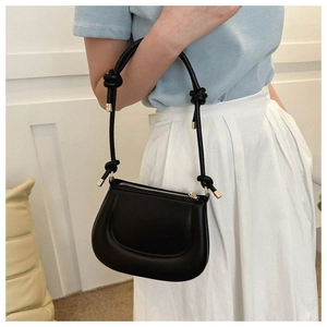 Détail du sac pois en cuir noir avec bandoulière à nœuds et design embossé en U