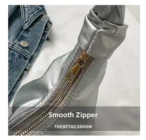 Detail view of smooth golden metal zipper on silver pleated metallic shoulder bag
