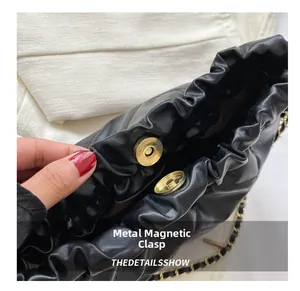 Close-up of magnetic snap closure and chain strap on black pleated bucket bag