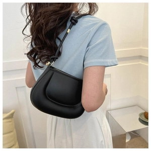 Détail du sac à bandoulière noir bouffant avec nœud sur la sangle et finition mate élégante