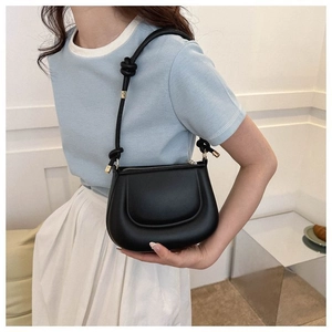 Détail du sac demi-lune noir avec bandoulière à nœud élégante et finitions dorées