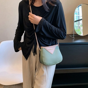 Sac seau en cuir vert avec rabat rose et garniture dorée porté par mannequin