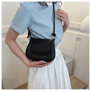 Détail du sac selle noir avec ferrures dorées sur mannequin en tenue décontractée chic