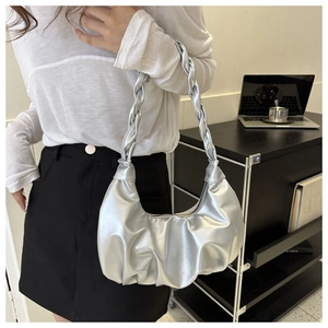 Detail of silver pleated crescent bag with thick woven handle in an office setting