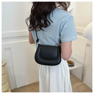 Gros plan d'un sac à bandoulière en cuir noir en forme de croissant au design minimaliste
