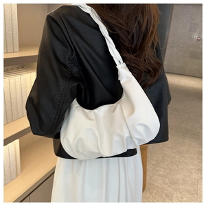 Detail of white pleated leather hobo bag with knotted strap worn on shoulder for commute