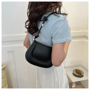 Détail du sac bouffant noir avec bandoulière nouée et finitions dorées sur modèle