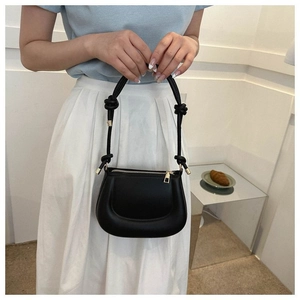 Détail du sac pois noir avec bandoulière nouée et finitions métalliques dorées