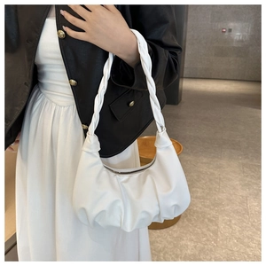 Detail of white pleated cloud bag featuring a woven strap and soft faux leather texture