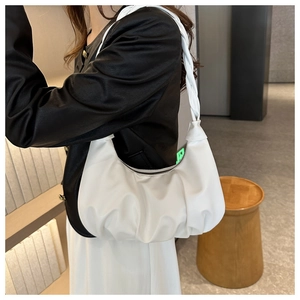 Detailed side view of a white pleated crescent bag featuring a braided shoulder strap