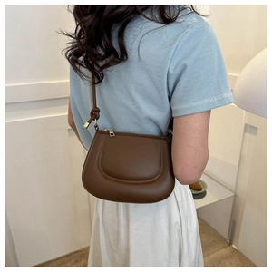 Détail du sac demi-lune marron avec ferrures dorées et bandoulière à nœuds élégante