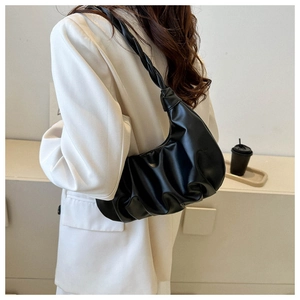 Detail of black pleated hobo bag with unique knotted strap on shoulder in office setting