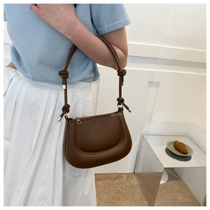Détail d'un sac en cuir marron avec bandoulière à nœud et garnitures dorées
