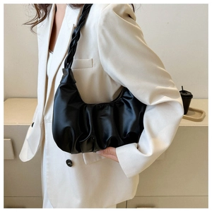 Detail of black pleated shoulder bag with unique braided strap and soft leather texture