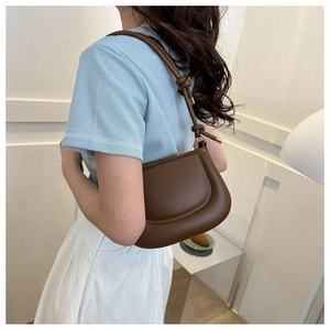 Détail du sac pois en cuir marron foncé avec une bandoulière à nœud au design unique