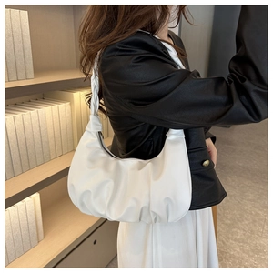 Detail view of a white pleated hobo bag showing its soft leather texture and crescent shape