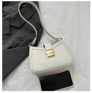 Close-up of white PU leather underarm bag with gold metal clasp on a grey blazer