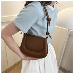 Détail du sac pois marron foncé montrant la bandoulière nouée et les ferrures dorées