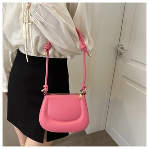 Détail du sac selle rose vif avec fermeture éclair dorée et bandoulière à cordon