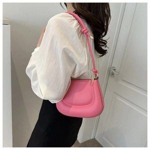 Détail du sac à bandoulière rose clair incurvé avec nœuds et garnitures dorées