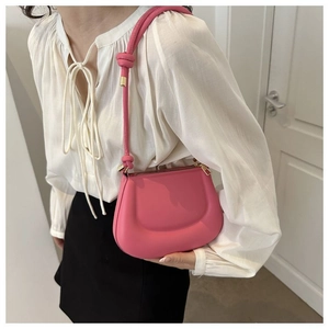 Détail d'un sac à bandoulière rose avec lanière nouée et éléments métalliques dorés