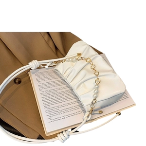 White ruched cloud crossbody bag with decorative pearl chain on a stylish blazer background