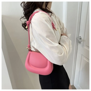 Détail du sac selle rose en demi-lune avec bandoulière nouée et texture cuir lisse