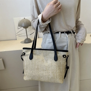 Grand sac cabas d'été en paille avec anses en cuir porté par un mannequin en extérieur